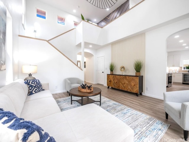 living room featuring a high ceiling, light hardwood / wood-style flooring, and wine cooler