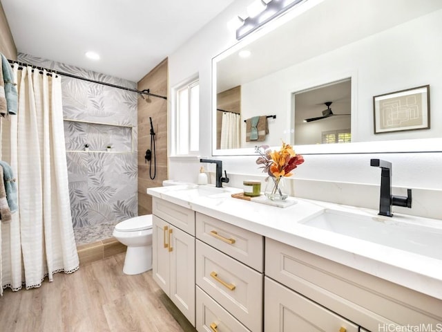 bathroom featuring vanity, ceiling fan, hardwood / wood-style flooring, toilet, and curtained shower