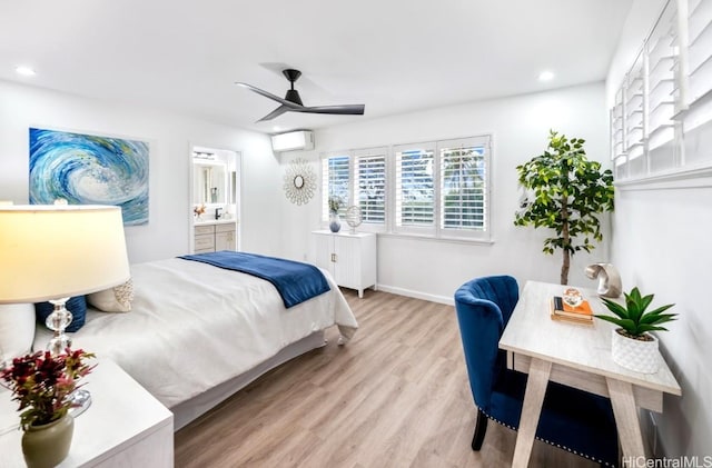 bedroom featuring ensuite bathroom, sink, ceiling fan, light wood-type flooring, and a wall unit AC