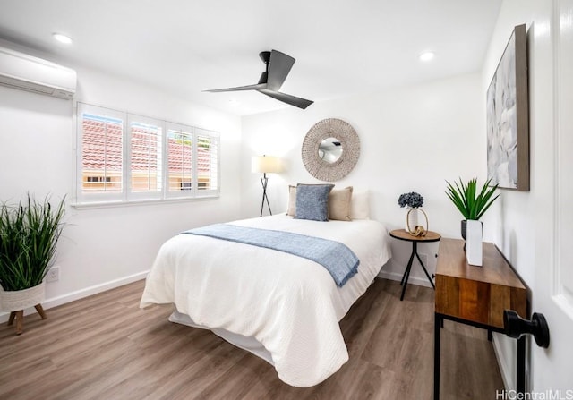 bedroom with a wall unit AC, ceiling fan, and hardwood / wood-style flooring