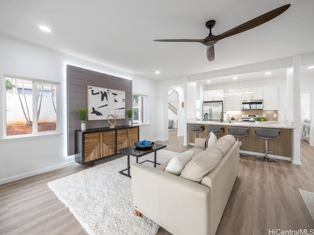 living room with ceiling fan, light hardwood / wood-style floors, and sink