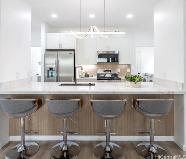 kitchen featuring a breakfast bar, white cabinetry, kitchen peninsula, and appliances with stainless steel finishes