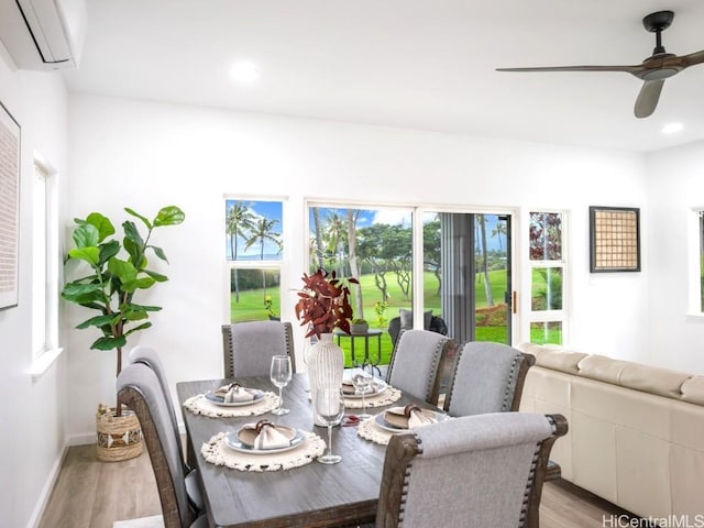 dining area with light hardwood / wood-style floors, an AC wall unit, and ceiling fan