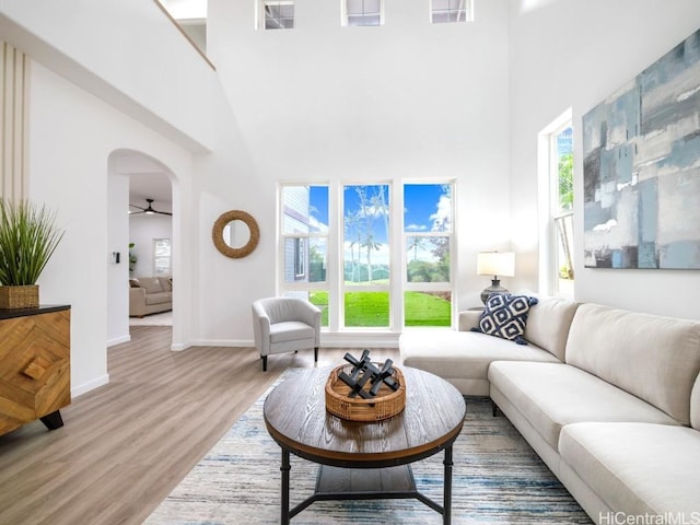 living room with ceiling fan, a high ceiling, and hardwood / wood-style flooring