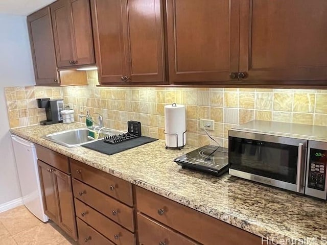 kitchen featuring light stone counters, dishwasher, light tile patterned flooring, and sink