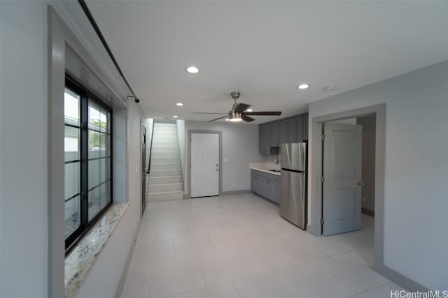 kitchen with gray cabinetry, ceiling fan, and stainless steel refrigerator