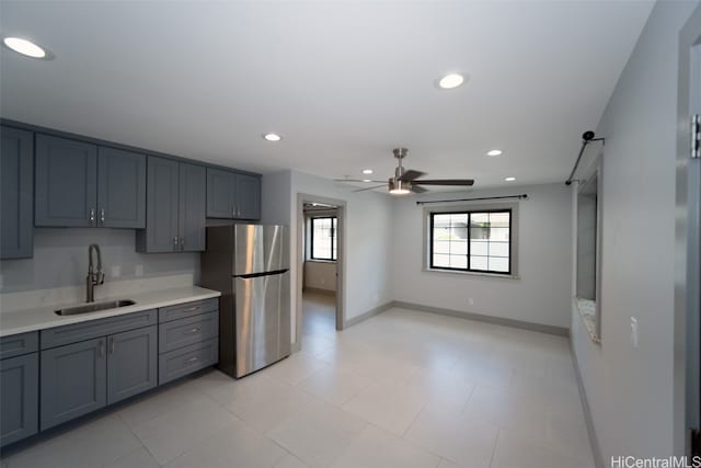 kitchen with stainless steel fridge, ceiling fan, gray cabinetry, and sink