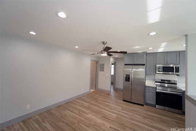 kitchen with gray cabinetry, ceiling fan, light wood-type flooring, and stainless steel appliances