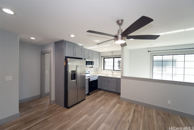 kitchen with ceiling fan, sink, gray cabinets, appliances with stainless steel finishes, and light wood-type flooring