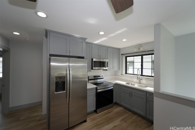 kitchen with dark wood-type flooring, sink, gray cabinets, and stainless steel appliances