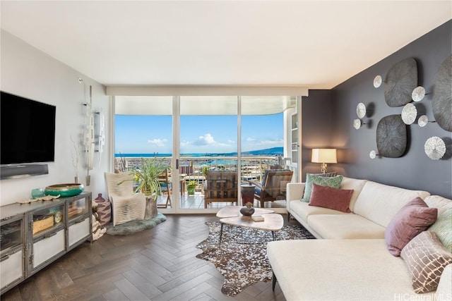 living room with dark parquet floors, a water view, and floor to ceiling windows