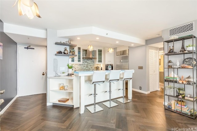 kitchen with stainless steel appliances, dark parquet floors, a kitchen bar, and kitchen peninsula