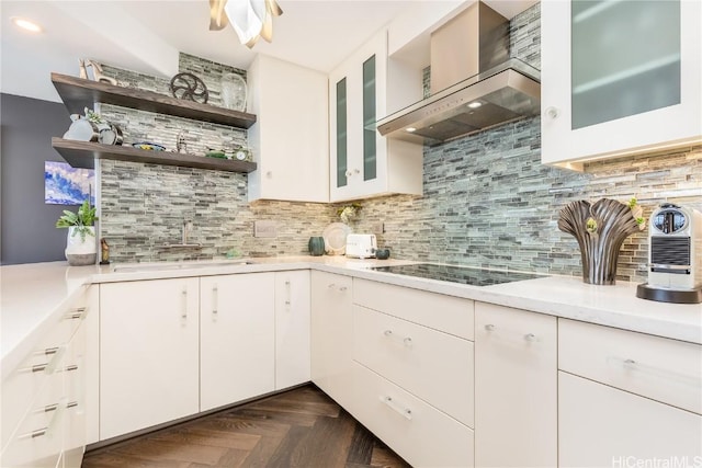 kitchen featuring white cabinets, black electric stovetop, wall chimney range hood, dark parquet floors, and decorative backsplash