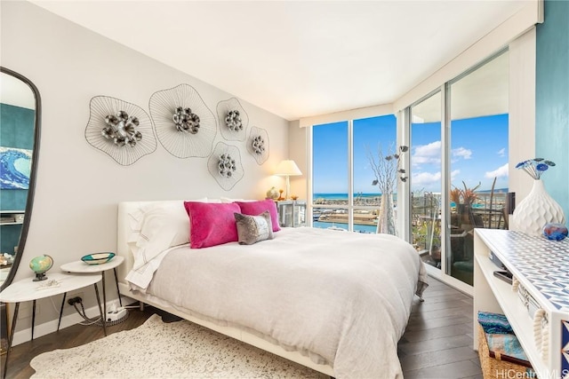 bedroom with a water view, access to outside, and dark hardwood / wood-style flooring