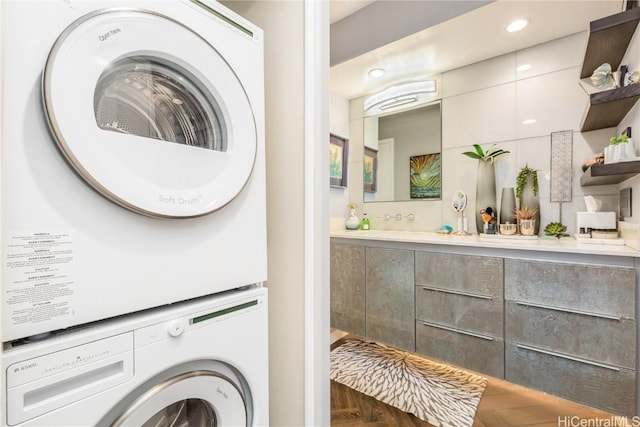 laundry room featuring dark parquet flooring and stacked washer / dryer