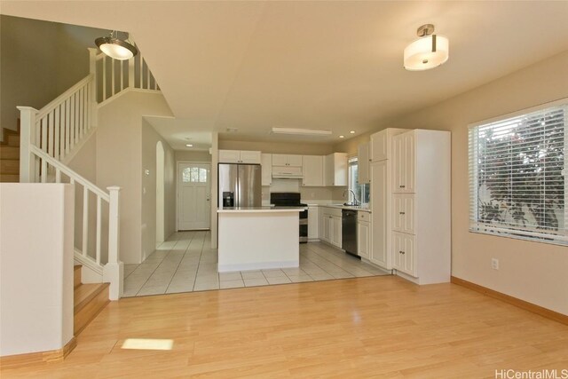 kitchen with white cabinetry, light hardwood / wood-style flooring, a kitchen island, and appliances with stainless steel finishes