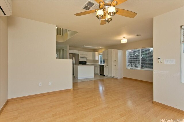 unfurnished living room featuring light wood-type flooring, an AC wall unit, and ceiling fan