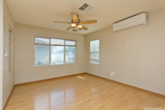 empty room with a wall mounted air conditioner, light hardwood / wood-style flooring, and ceiling fan