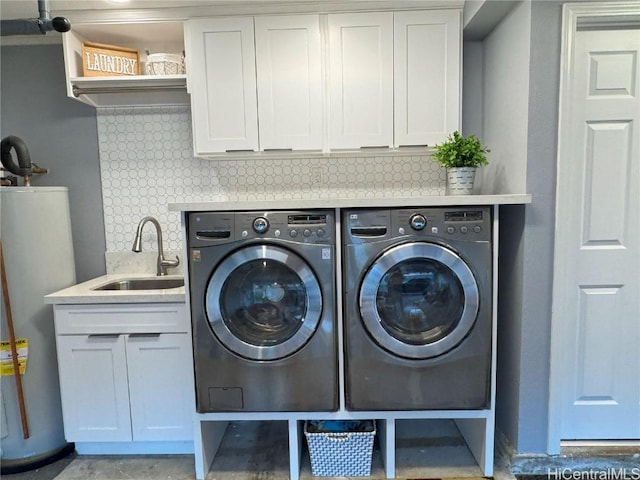 washroom featuring washing machine and clothes dryer, water heater, sink, and cabinets