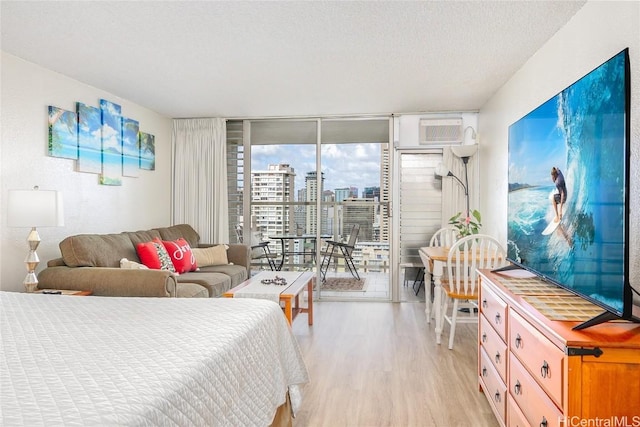 bedroom with floor to ceiling windows, access to exterior, light hardwood / wood-style floors, and a textured ceiling