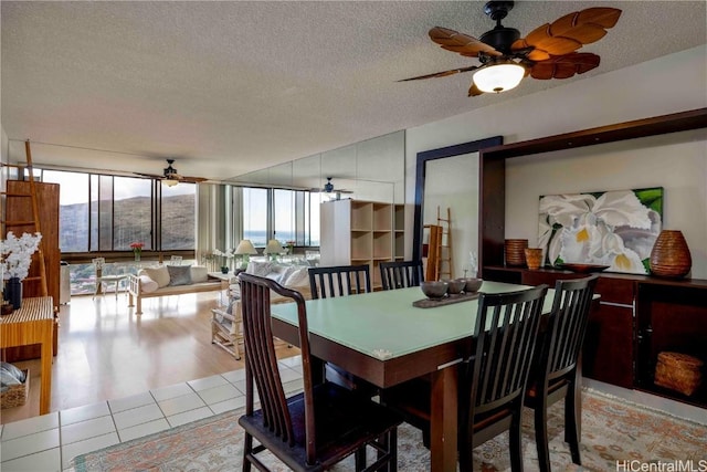 dining area with expansive windows, light tile patterned flooring, and a textured ceiling