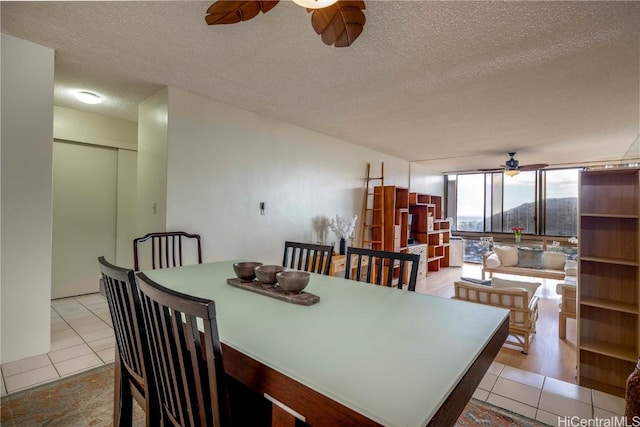 dining space with ceiling fan, expansive windows, light tile patterned floors, and a textured ceiling