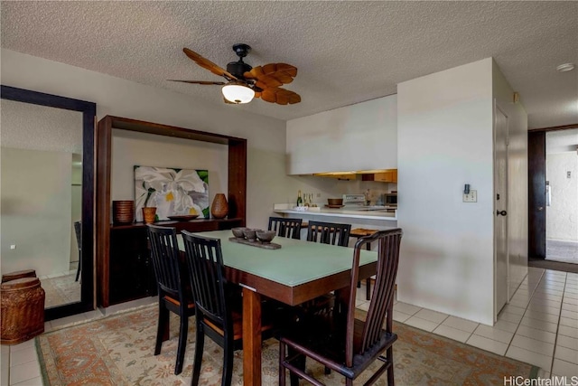 dining area featuring ceiling fan, light tile patterned flooring, and a textured ceiling