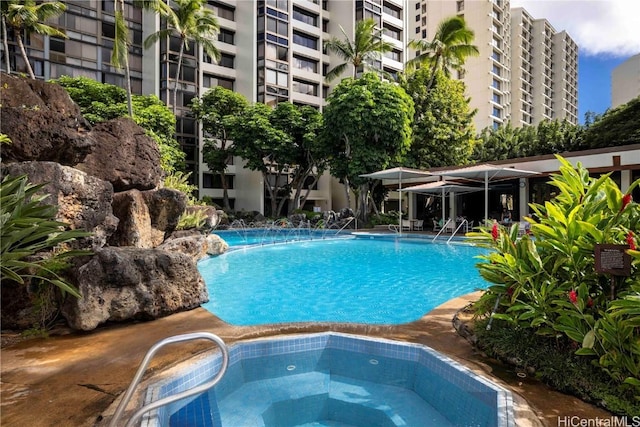 view of pool with pool water feature and a hot tub