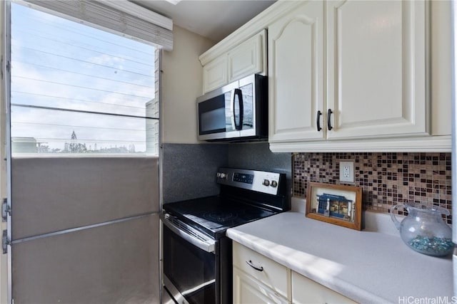 kitchen featuring white cabinets, appliances with stainless steel finishes, and tasteful backsplash