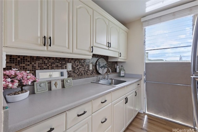 kitchen featuring light hardwood / wood-style floors, white cabinetry, sink, and tasteful backsplash