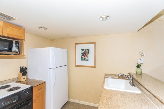 kitchen with electric stove, sink, and white refrigerator