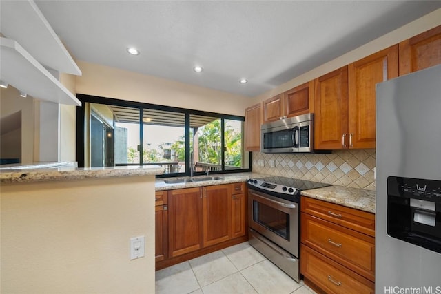 kitchen featuring tasteful backsplash, light stone counters, light tile patterned floors, and stainless steel appliances