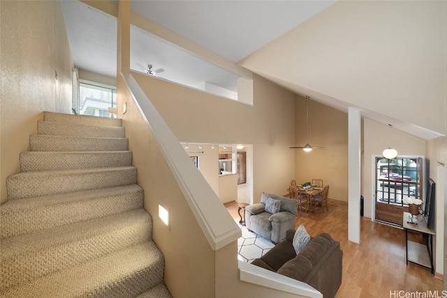 staircase with ceiling fan, wood-type flooring, and lofted ceiling