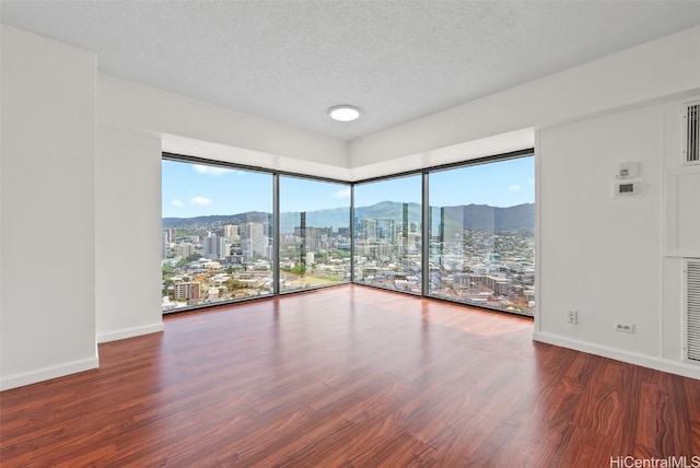 spare room with wood-type flooring, a mountain view, and a textured ceiling