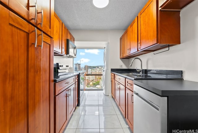 kitchen with light tile patterned flooring, stainless steel appliances, sink, and a textured ceiling