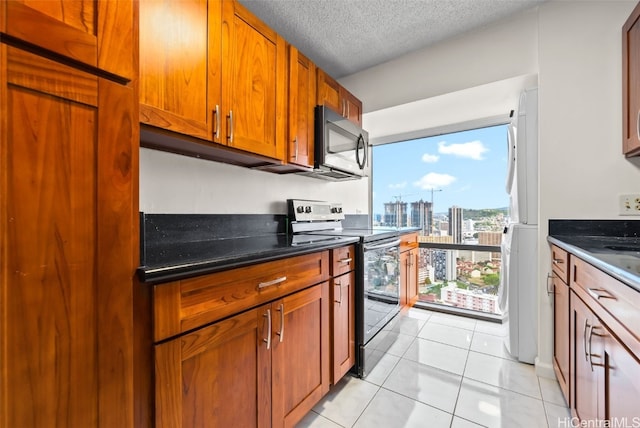 kitchen featuring white fridge, light tile patterned floors, a textured ceiling, and range with electric stovetop