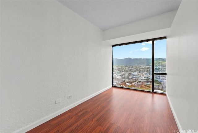 empty room with a healthy amount of sunlight, hardwood / wood-style floors, and a textured ceiling