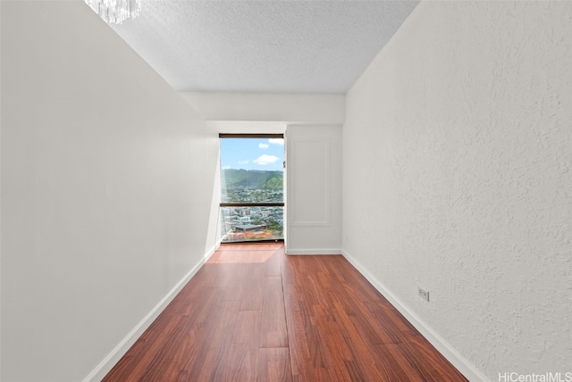 unfurnished room featuring hardwood / wood-style flooring and a textured ceiling