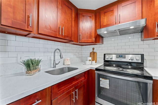 kitchen featuring decorative backsplash, sink, light stone countertops, and stainless steel range with electric stovetop