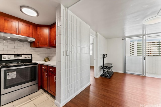 kitchen featuring backsplash, light tile patterned floors, and stainless steel electric range oven