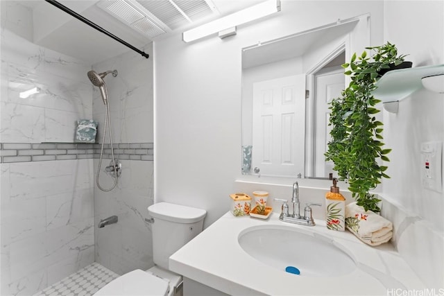 bathroom with tiled shower, toilet, and vanity