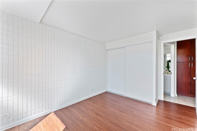 empty room featuring hardwood / wood-style floors and tile walls