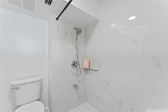 bathroom with a tile shower and toilet