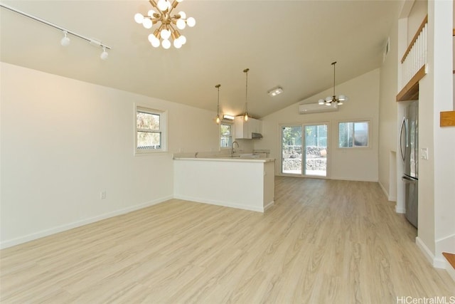 kitchen featuring white cabinets, a notable chandelier, kitchen peninsula, and decorative light fixtures