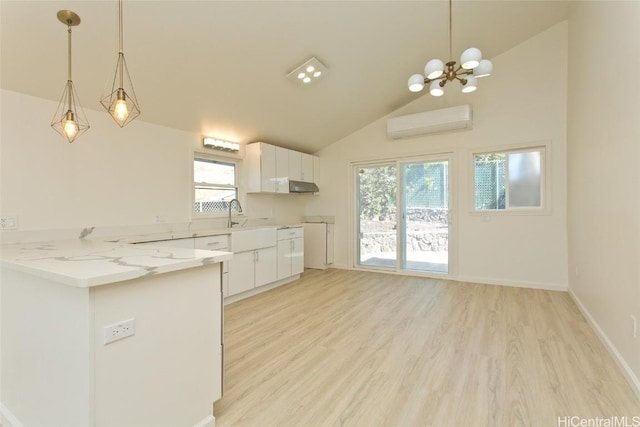 kitchen featuring kitchen peninsula, a wall unit AC, decorative light fixtures, light hardwood / wood-style flooring, and white cabinets