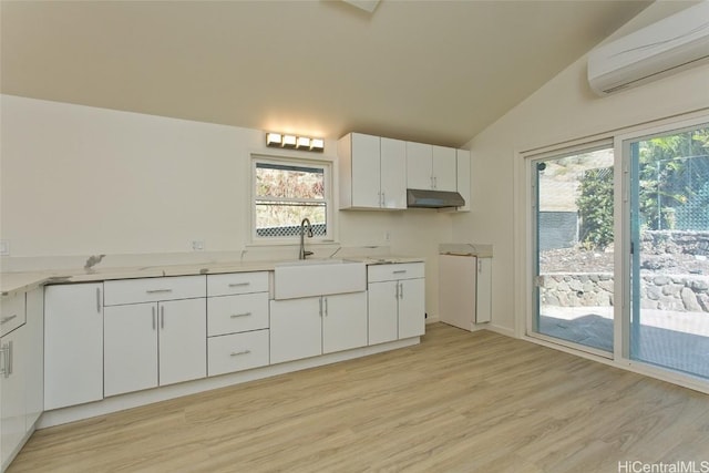 kitchen featuring white cabinetry, a wall mounted AC, plenty of natural light, and sink