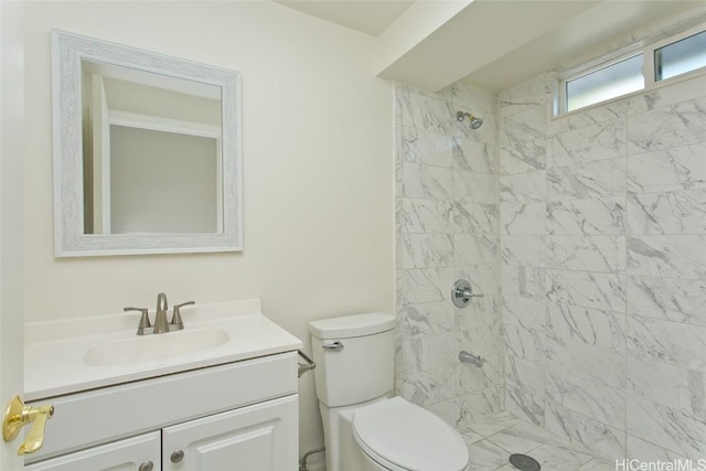 bathroom with tiled shower, vanity, and toilet