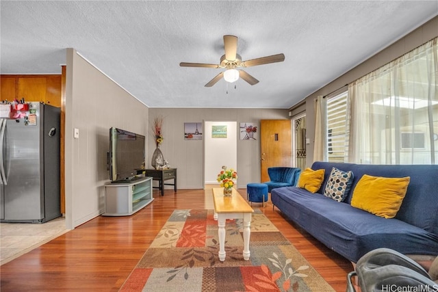 living room with ceiling fan, wood-type flooring, and a textured ceiling