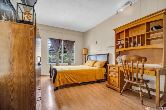 bedroom featuring track lighting and light hardwood / wood-style flooring