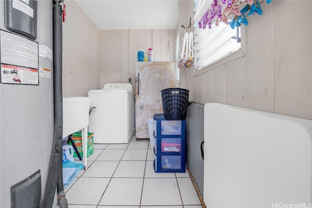 washroom featuring wood walls, light tile patterned flooring, sink, and washer / clothes dryer